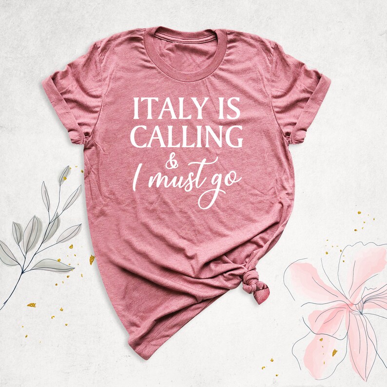May include: A pink t-shirt with the text "ITALY IS CALLING & I must go" in white lettering.