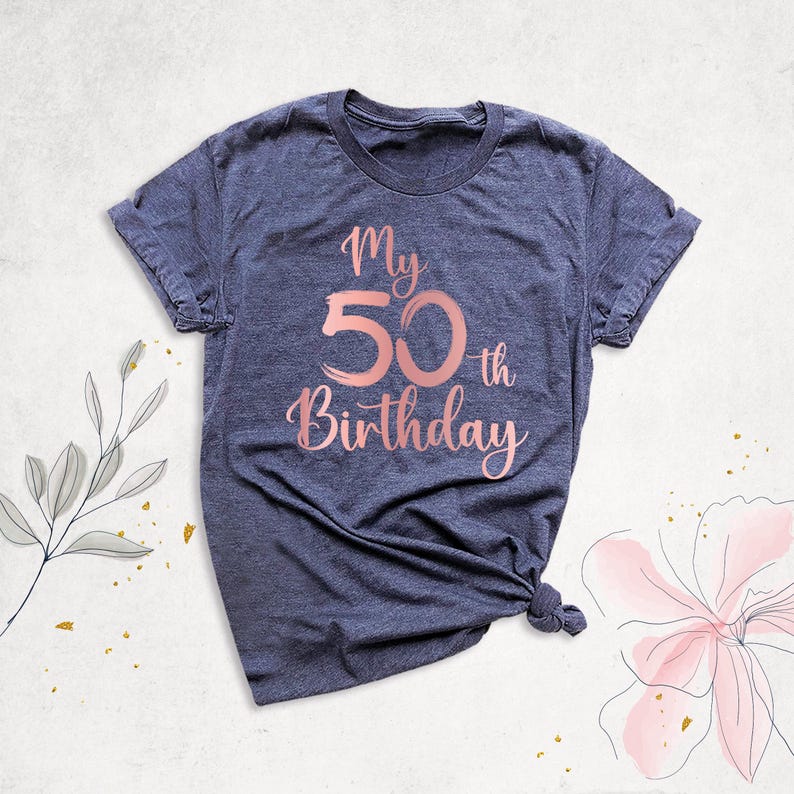 May include: A dark blue t-shirt with the text "My 50th Birthday" in rose gold lettering.