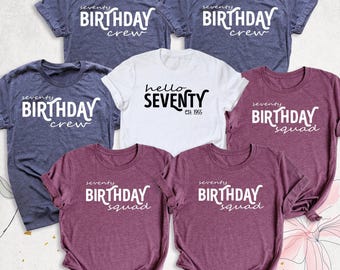 May include: A collection of seven short-sleeved t-shirts in heathered blue, white, and maroon. The blue and maroon shirts feature white text reading seventy BIRTHDAY crew or squad. The white shirt features black text reading hello SEVENTY est. 1955.