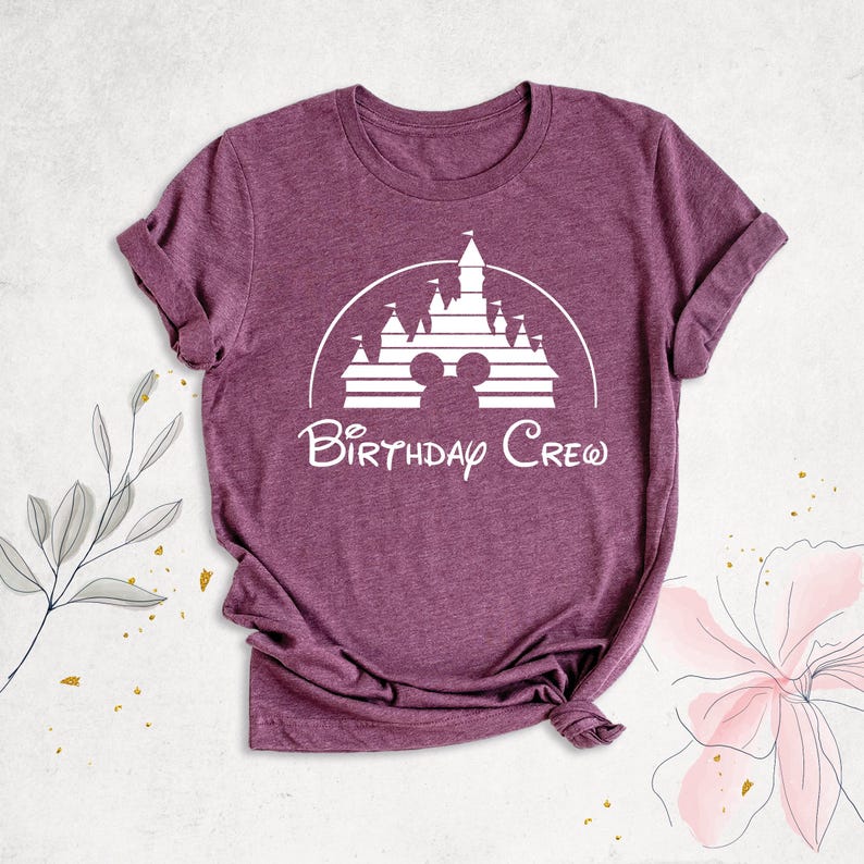May include: Purple t-shirt with a white graphic of Cinderella's castle and Mickey Mouse ears with the text "Birthday Crew".