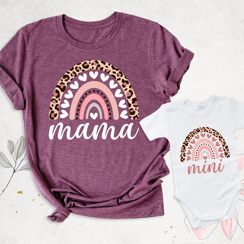 Puede incluir: Un conjunto de dos camisetas con un arco&iacute;ris con detalles de estampado de leopardo y corazones. La camiseta m&aacute;s grande dice "mama" y la m&aacute;s peque&ntilde;a dice "mini".