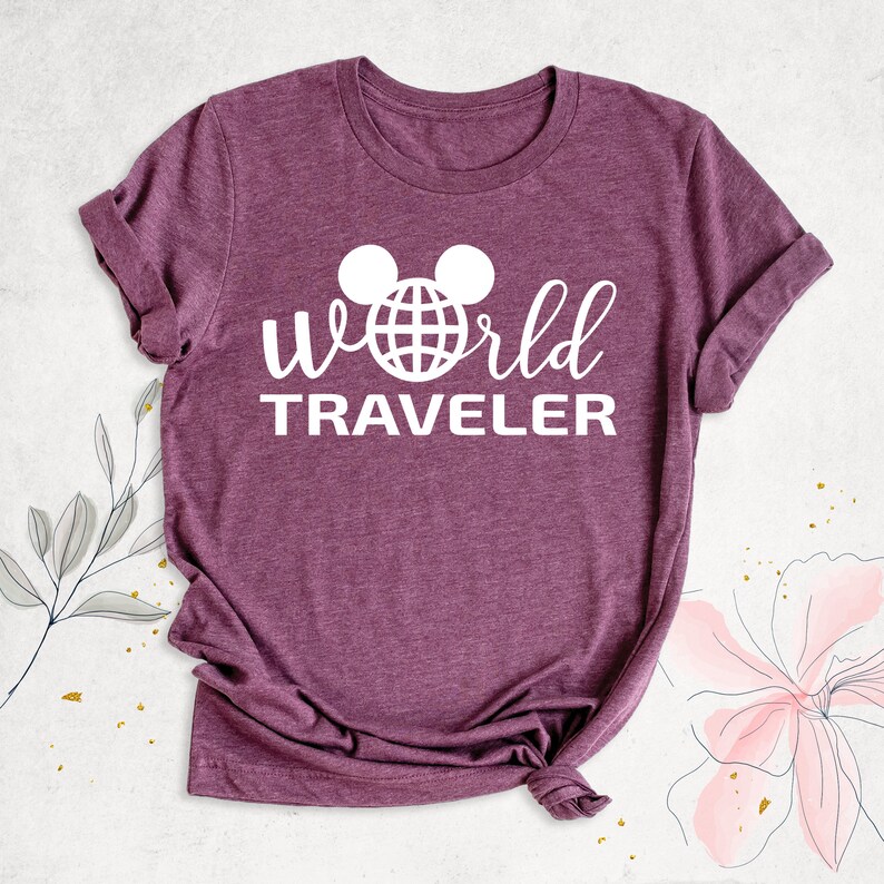 May include: A purple t-shirt with a white graphic of a Mickey Mouse head with a globe inside the ears and the text "world traveler" underneath.
