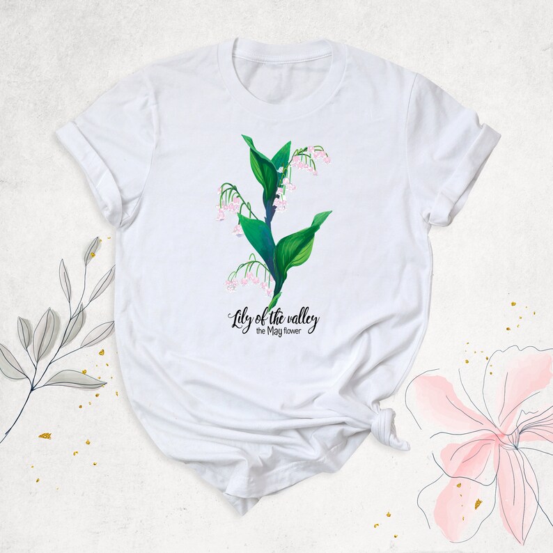 May include: White t-shirt with a green lily of the valley flower design and the text "Lily of the valley the May flower".