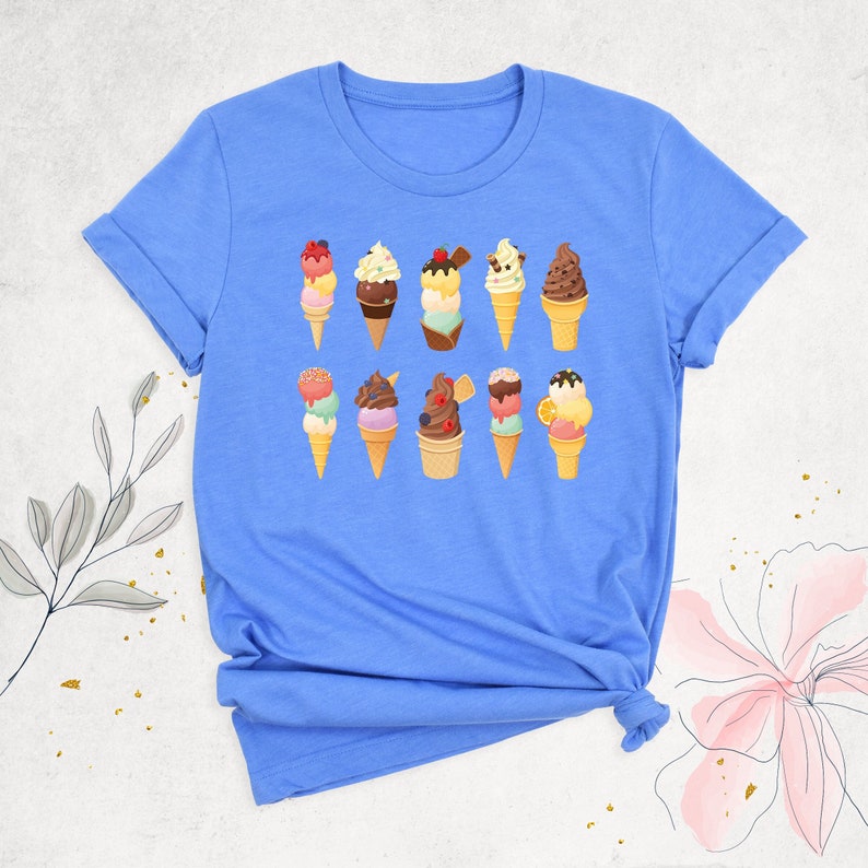 May include: A light blue t-shirt with a graphic of nine colorful ice cream cones. The ice cream cones are decorated with different toppings, including sprinkles, chocolate chips, and fruit.