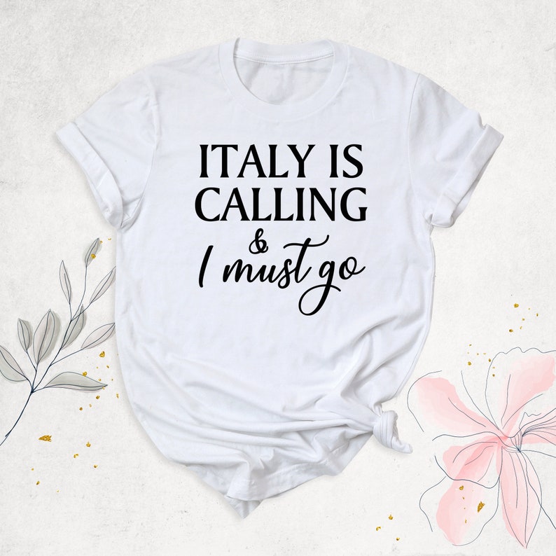 May include: White t-shirt with black text that reads "ITALY IS CALLING & I must go".