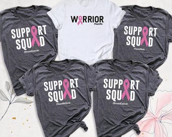 May include: Five short-sleeved t-shirts. One white shirt features the text WARRIOR with a pink ribbon. Four dark gray heather shirts feature the text SUPPORT SQUAD with a pink ribbon and various hashtags including #BreastCancer, #TeamMom, and #TeamMelissa.