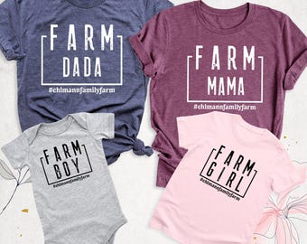 May include: A navy blue t-shirt with white text reading FARM DADA, a maroon t-shirt with white text reading FARM MAMA, a gray baby bodysuit with black text reading FARM BOY, and a light pink t-shirt with black text reading FARM GIRL.