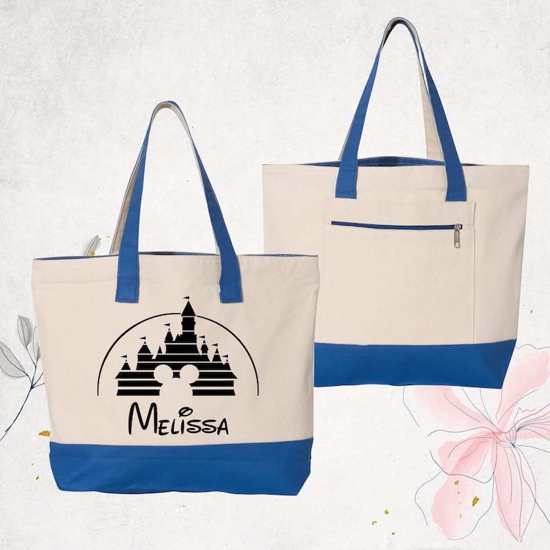 Pu&ograve; includere: Una borsa tote in tela bianca con bordatura blu e una silhouette nera del castello Disney con le orecchie di Topolino al centro. Il nome "Melissa" &egrave; stampato sotto il castello. La borsa ha una tasca con cerniera sul retro.
