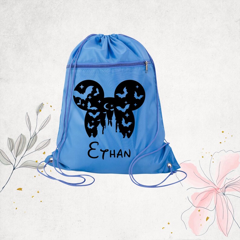 Pu&ograve; includere: Uno zaino con coulisse azzurro con una grafica nera a forma di silhouette di orecchie di topo riempita di pipistrelli, stelle e una mezzaluna. Sotto la grafica, il nome Ethan &egrave; stampato in un carattere nero in stile manoscritto.