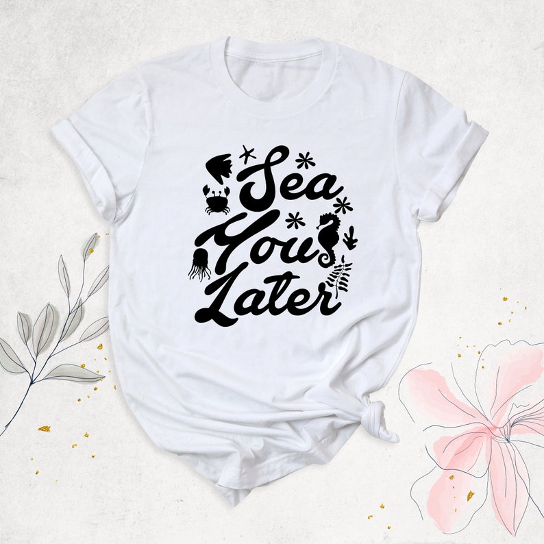Peut inclure: T-shirt blanc avec un motif noir qui dit "Sea You Later" avec des illustrations de la vie marine.