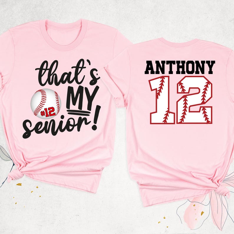 May include: Pink baseball themed t-shirt with the text "that's my senior!" and a baseball with the number 12 on it. The back of the shirt has the name "ANTHONY" and the number 12 in a baseball design.