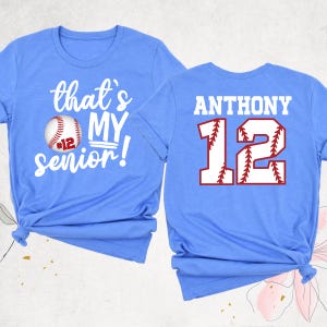 May include: Two light blue t-shirts with a baseball theme. The front shirt says "that's my senior!" with a baseball graphic. The back shirt says "ANTHONY 12" with a baseball graphic.