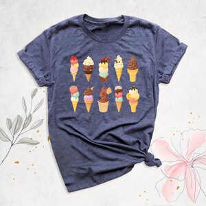 May include: A dark blue t-shirt with a design of various ice cream cones in different colors and flavors. The ice cream cones are arranged in two rows of five.