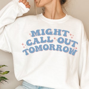 Puede incluir: Sudadera blanca con texto azul y rosa que dice "MIGHT CALL OUT TOMORROW" con pequeñas estrellas alrededor del texto.