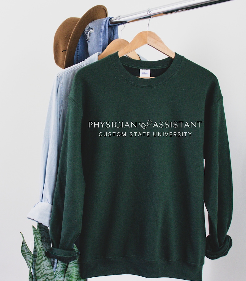 May include: A dark green sweatshirt with the text "PHYSICIAN ASSISTANT CUSTOM STATE UNIVERSITY" printed on the front.