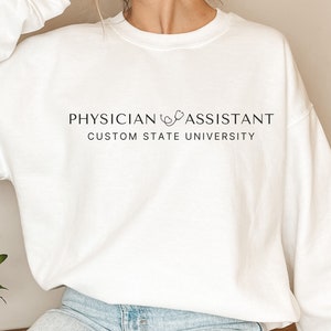 May include: White sweatshirt with the text "PHYSICIAN ASSISTANT CUSTOM STATE UNIVERSITY" and a stethoscope graphic.