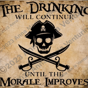 以下が含まれることがあります： 「The Drinking Will Continue Until The Morale Improves」というテキストが入った、ヴィンテージスタイルの海賊のドクロとクロスボーンのグラフィック。背景は、地図のようなパターンが描かれた、色あせた茶色の羊皮紙です。
