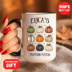 May include: A white ceramic mug with a black handle and rim, featuring a graphic of nine pumpkins in various patterns and colors. The text "ERICA'S" is printed above the pumpkins, and the text "PUMPKIN PATCH" is printed below the pumpkins.