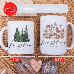 May include: Two white ceramic mugs, one with a forest design and the other with floral art. The mugs are labeled "Mr. Williams" and "Mrs. Williams" with "EST. 2024". The mugs are approximately 3.75" and 4.6" tall.
