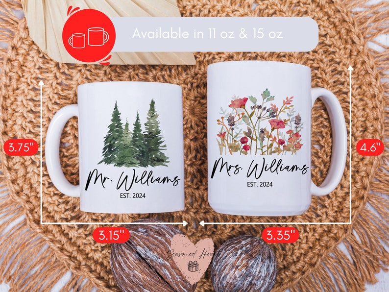 May include: Two white ceramic mugs, one with a forest design and the other with floral art. The mugs are labeled "Mr. Williams" and "Mrs. Williams" with "EST. 2024". The mugs are approximately 3.75" and 4.6" tall.