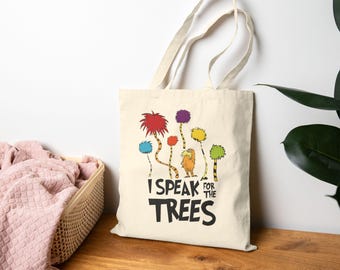 Könnte beinhalten: Beige Canvas-Tragetasche mit einer farbenfrohen Illustration von skurrilen Bäumen und einer Figur. Der Text "I SPEAK FOR THE TREES" ist in Schwarz gedruckt. Die Tasche hat zwei Griffe.