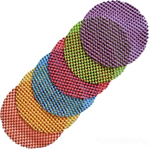 May include: A set of six circular coasters arranged in a diagonal overlapping line. Each coaster features a textured, grid-like pattern in a distinct color: purple, lime green, red, blue, yellow, and orange, creating a vibrant, multi-colored display.