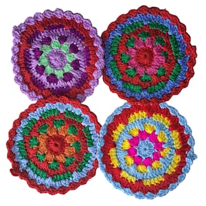 May include: Four colorful, handmade crochet coasters. Each coaster features a circular design with concentric rings of various colors, including red, blue, green, yellow, orange, and purple. The edges have a scalloped trim.