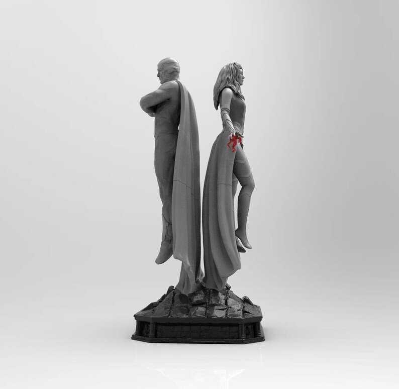 Op de afbeelding: Een grijs en wit beeld van twee figuren die op een zwarte basis staan. De figuren dragen mantels en zijn dramatisch geposeerd. Het beeld is een verzamelstuk.