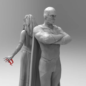 Op de afbeelding: Een grijs beeldje van een superheldenpaar. De mannelijke figuur staat met gekruiste armen, terwijl de vrouwelijke figuur met haar armen langs haar zijde staat. De mannelijke figuur heeft een rode helm en een cape.
