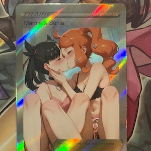 Könnte beinhalten: Eine holografische Trainerkarte mit den Charakteren Marnie & Sonia. Die Illustration zeigt zwei sich küssende Frauen mit einer sanften Farbpalette. Die Karte hat einen goldenen Rand und den Text "Du kannst nur 1 Unterstützerkarte während deines Zuges spielen."