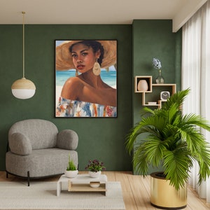 Puede incluir: Una impresión artística enmarcada de una mujer con sombrero de paja y pendientes, con una escena de playa de fondo. La mujer lleva un top con hombros descubiertos con estampados florales y a rayas. La obra se exhibe en un salón.