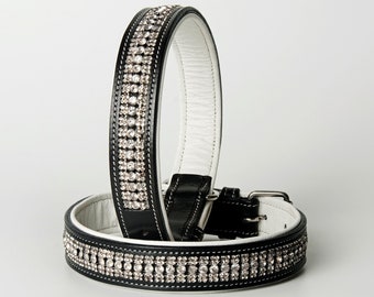 May include: Two black leather dog collars with white stitching and rows of clear rhinestones. The collars are stacked on top of each other.  Article No. 9010.
