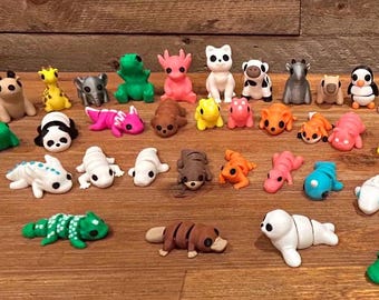 Puede incluir: Una colección de figuritas de animales coloridas hechas de arcilla polimérica. Las figuritas incluyen una variedad de animales, como un pingüino, un panda, una rana, un ornitorrinco, una oruga, una foca, un conejo, una tortuga, un lagarto y una variedad de otros animales.