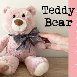 May include: A pink teddy bear with a grey and white bow tie. The bear is sitting on a wooden surface. The text "Sewing DIY Teddy Bear" is visible in the background.