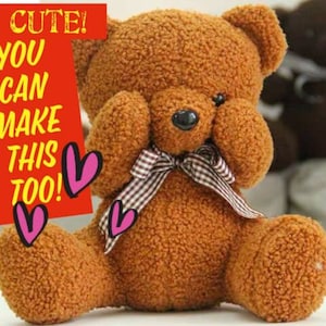 Pu&ograve; includere: Un orsacchiotto di peluche marrone con un fiocco a quadri &egrave; seduto con le zampe che gli coprono gli occhi. L'orsacchiotto ha un'espressione carina sul viso.