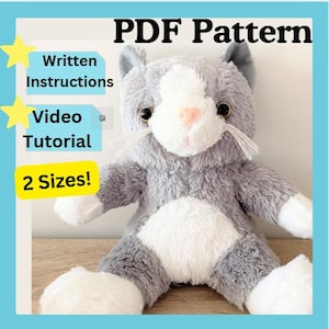 Puede incluir: Un gato de peluche gris y blanco con una nariz rosa y bigotes. La imagen incluye el texto "PDF Pattern", "Written Instructions", "Video Tutorial" y "2 Sizes!"
