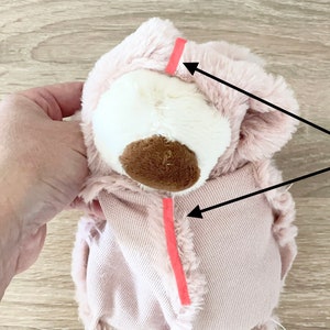 May include: Pink plush toy head with a brown nose and white fur. Two pink seams are marked with red tape. The text reads "When head inserted into the body, these two seams must be aligned together."