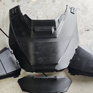 May include: A set of four black plastic pieces that appear to be part of a car's front bumper.