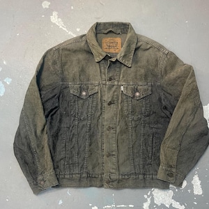 Op de afbeelding: Een corduroy jasje in een verbleekte olijfgroene kleur. De jas heeft een knoopsluiting, twee borstzakken en twee zijzakken. Een klein bruin label is zichtbaar op de kraag. Klassieke stijl.