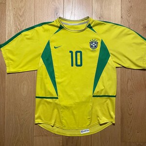 Puede incluir: Una camiseta de f&uacute;tbol amarilla de Brasil con detalles verdes y el n&uacute;mero 10 en el centro. La camiseta presenta un logotipo de Nike y el escudo del equipo de Brasil. La camiseta es de manga corta.