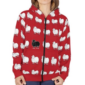 May include: Red zippered hoodie with a black and white sheep pattern. The hoodie has a black zipper and a black hood. The sheep are all white except for one black sheep.