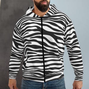 May include: A black and white zebra print zip-up hoodie. The hoodie features a full-length zipper, a hood, and long sleeves. The zebra pattern covers the entire garment, creating a bold and eye-catching design.