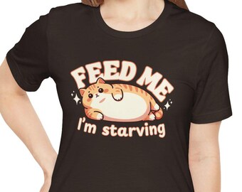 May include: Black t-shirt featuring a cartoon cat and the text "Feed Me I'm starving".