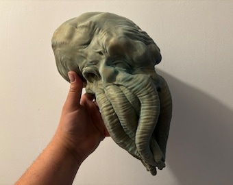 May include: A green and gray sculpted head of a creature with tentacles. The head is detailed with wrinkles and folds.