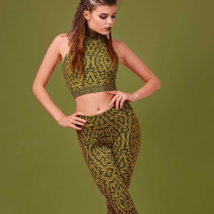 Peut inclure: Une femme portant un haut court et un legging à motifs verts et jaunes. Elle est debout, les jambes croisées, et porte des bottines marron.