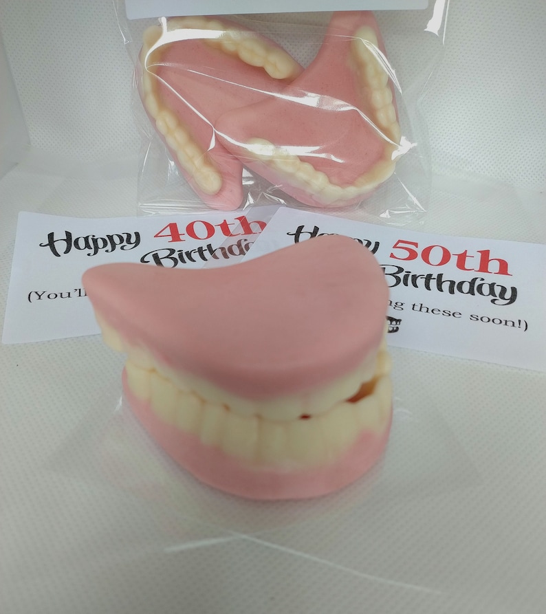 May include: Two sets of novelty plastic dentures in a clear plastic bag. The dentures are pink and white and have the text "Happy 40th Birthday" and "Happy 50th Birthday" on the cards behind them.