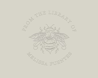 May include: A white and grey embossed logo with the text "From the Library of Melissa Fuentes" in a circle around a stylised bee with wings and a flower.