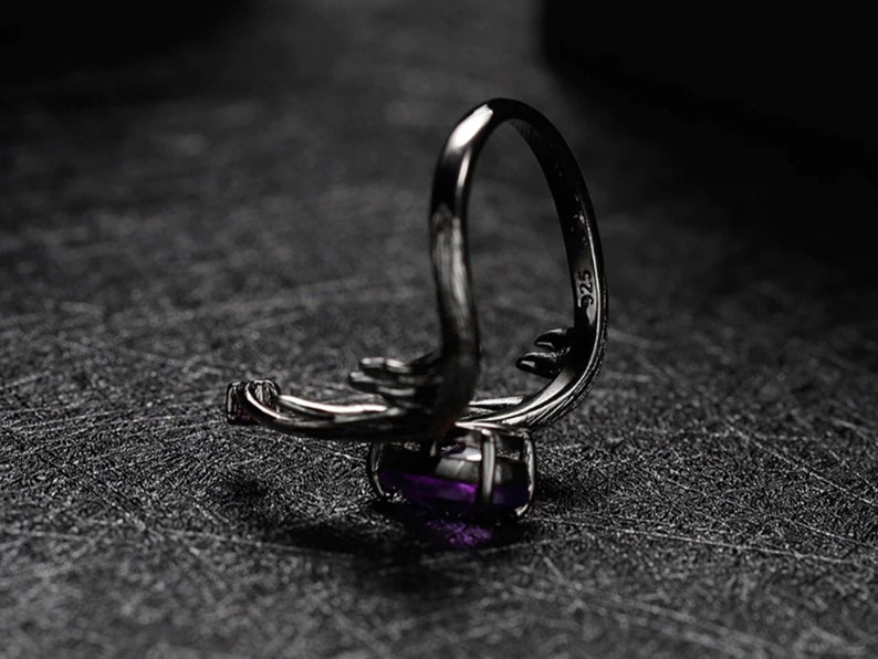 May include: A silver ring with a purple gemstone and the inscription "925" on the band.