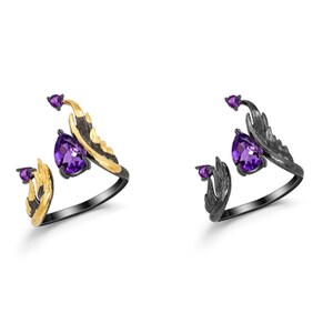 May include: Two silver rings with amethyst stones and gold accents. The rings are designed with a wing-like shape.