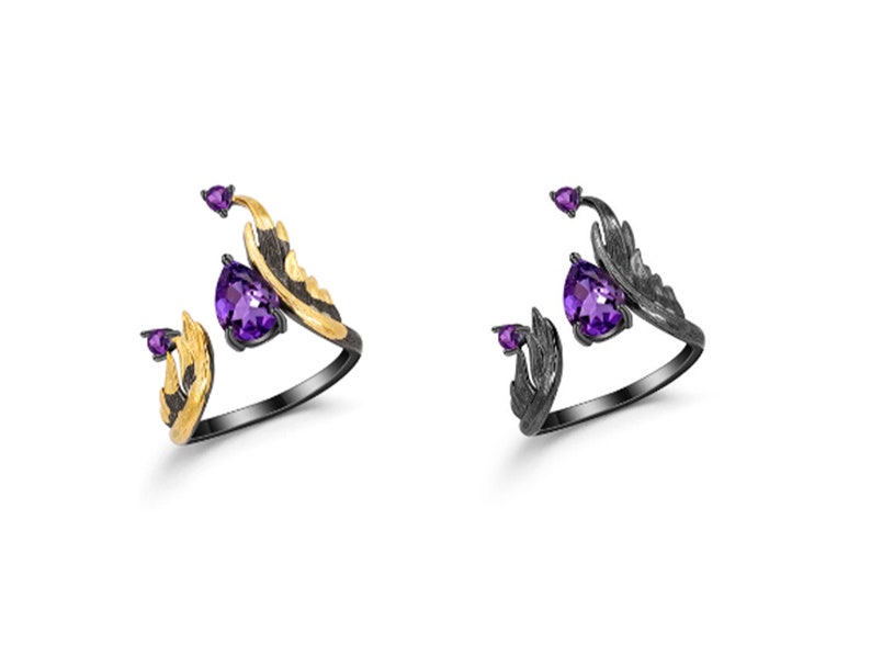 May include: Two silver rings with amethyst stones and gold accents. The rings are designed with a wing-like shape.